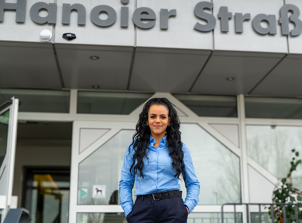 Concierge-Service Hanoier Straße Concierge-Mitarbeiterin steht vor dem Eingangsbereich eines Wohngebäudes in der Hanoier Straße.