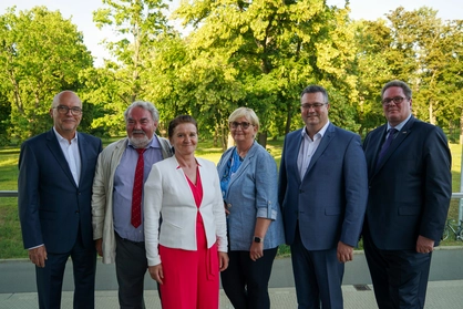 Aufsichtsrat Titelbild 2025 Sechs Personen in formeller Kleidung stehen für ein Gruppenfoto im Grünen