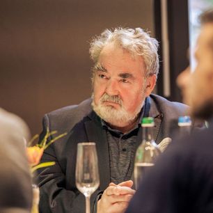 Aufsichtsratsvorsitzender der WBG Erfurt sitzt auf einer Veranstaltung mit Anzug an einem Tisch